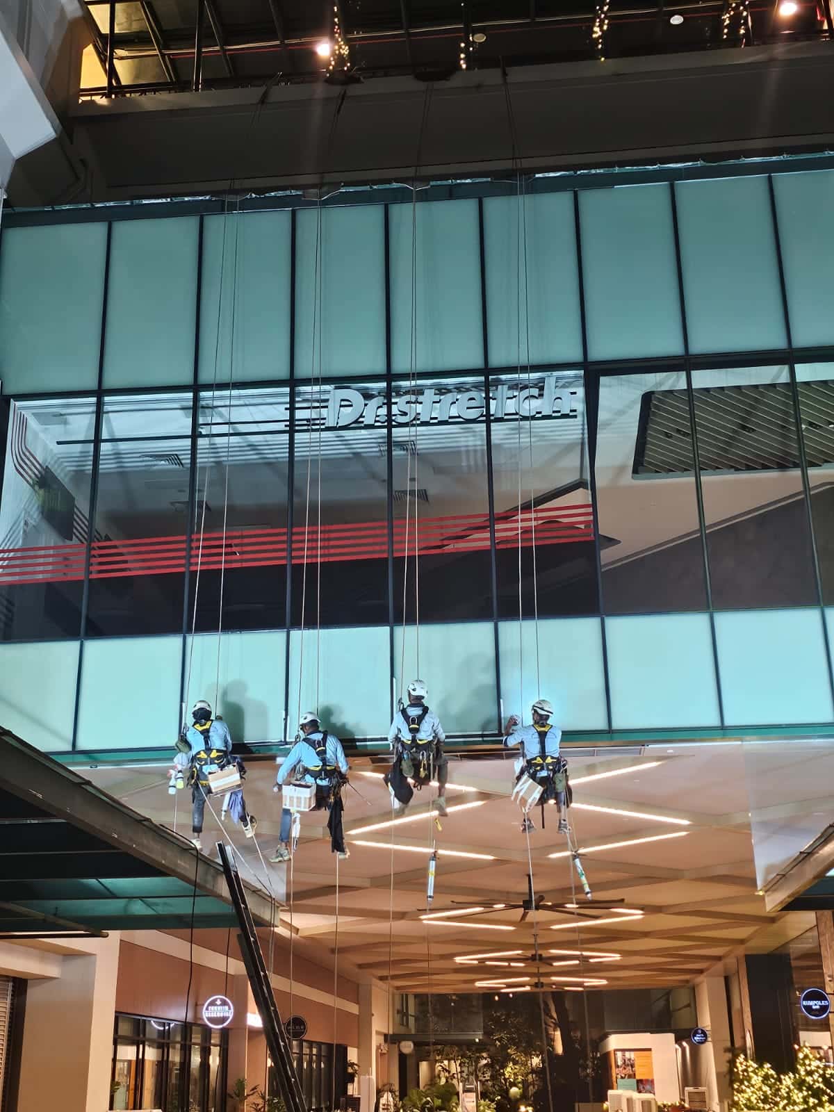 Rope-access works on a commercial mall façade in Singapore at night