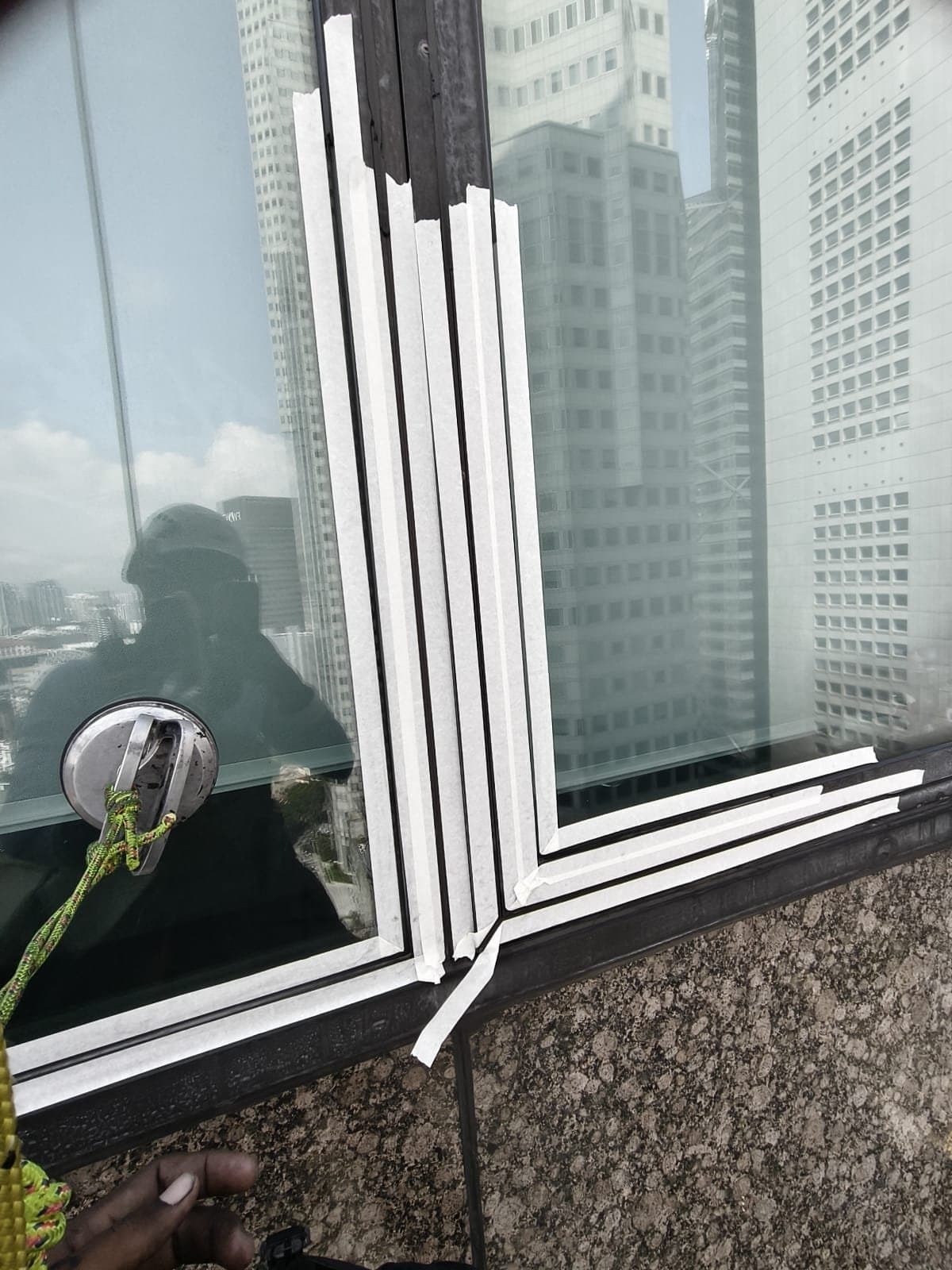 Hydroseal IRATA rope-access technician in helmet and PPE working at height on freshly taped façade sealant joints on a Grade-A office tower in Singapore’s CBD