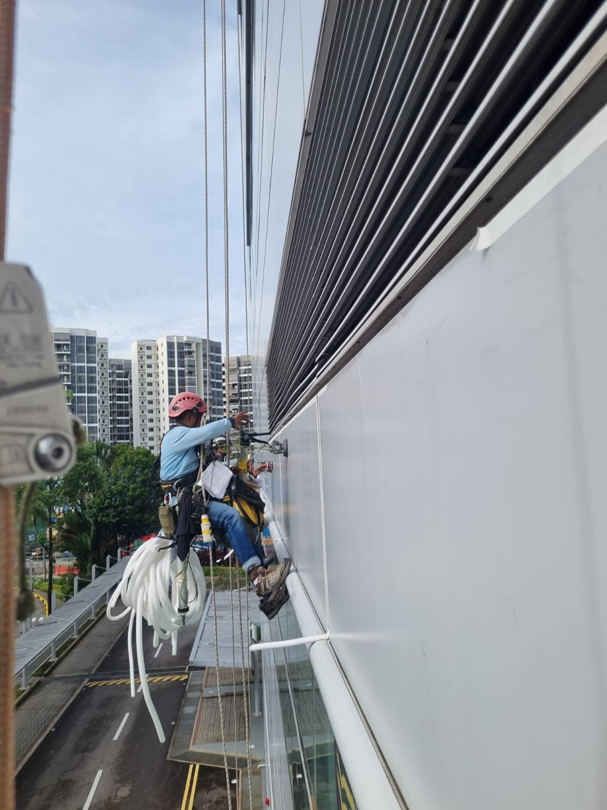 Hydroseal rope-access technicians replacing façade sealant on the louvred curtain wall of a seafront condominium in the East Coast area of Singapore