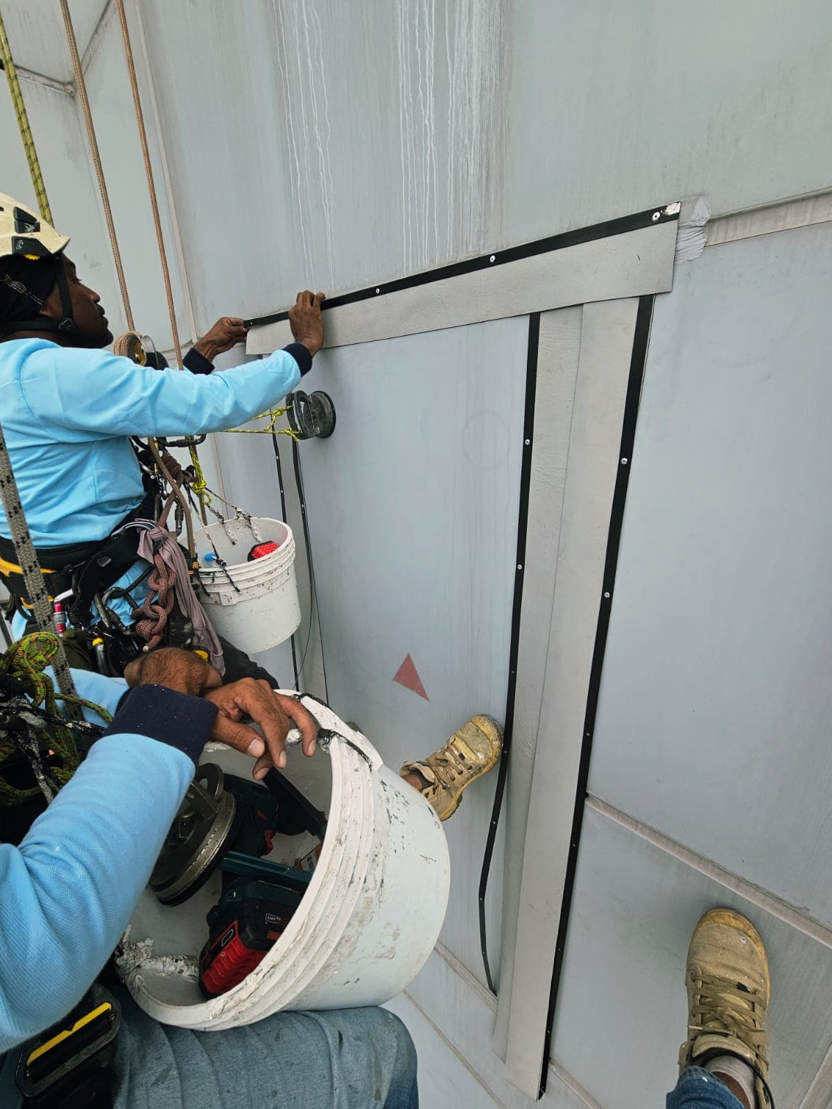 Hydroseal rope-access technician replacing sealant on an external wall joint in Singapore
